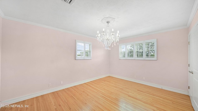 unfurnished room featuring a notable chandelier, crown molding, wood finished floors, and baseboards