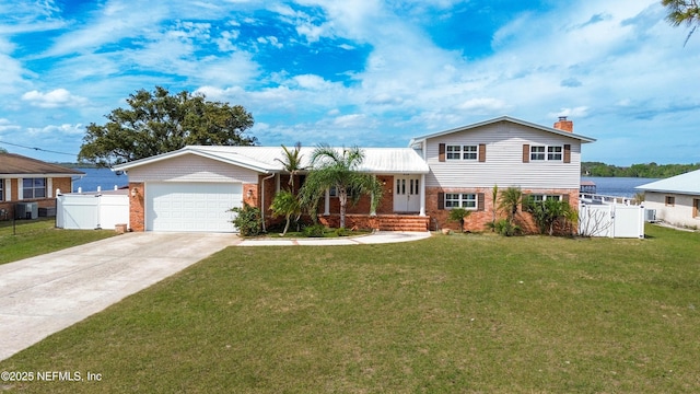 tri-level home with a gate, fence, concrete driveway, and brick siding