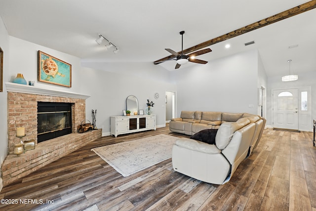 living room featuring vaulted ceiling with beams, a fireplace, wood finished floors, and baseboards