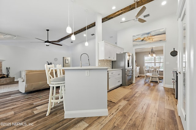 kitchen featuring open floor plan, visible vents, stainless steel fridge with ice dispenser, and wood finished floors