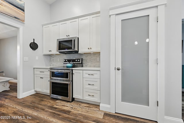 kitchen featuring light countertops, appliances with stainless steel finishes, dark wood-style flooring, and tasteful backsplash