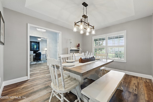 dining room with a notable chandelier, baseboards, and wood finished floors