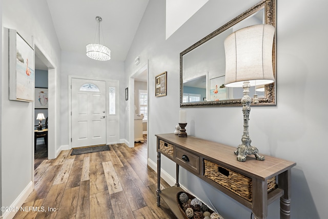 foyer with lofted ceiling, baseboards, and hardwood / wood-style floors