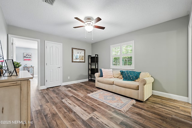 living area with baseboards, a textured ceiling, visible vents, and dark wood-style flooring