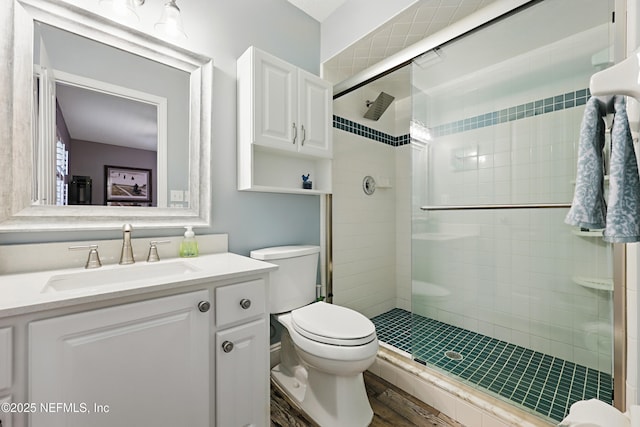 full bathroom with wood finished floors, a shower stall, toilet, and vanity