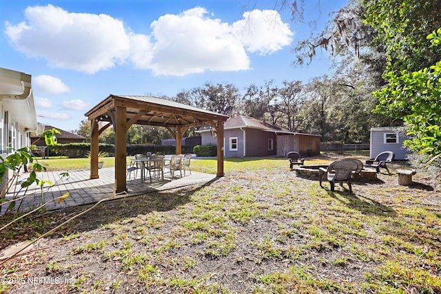 view of yard featuring a fire pit, an outdoor structure, fence, a gazebo, and a patio area