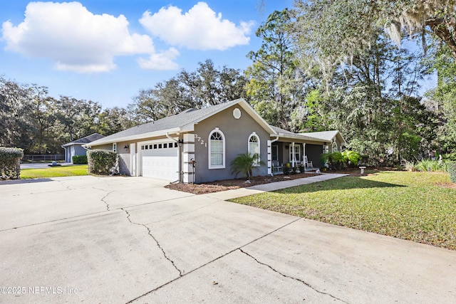 ranch-style home featuring a garage, a front yard, driveway, and stucco siding