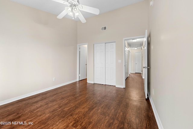 unfurnished bedroom with dark wood-type flooring, visible vents, baseboards, a closet, and attic access