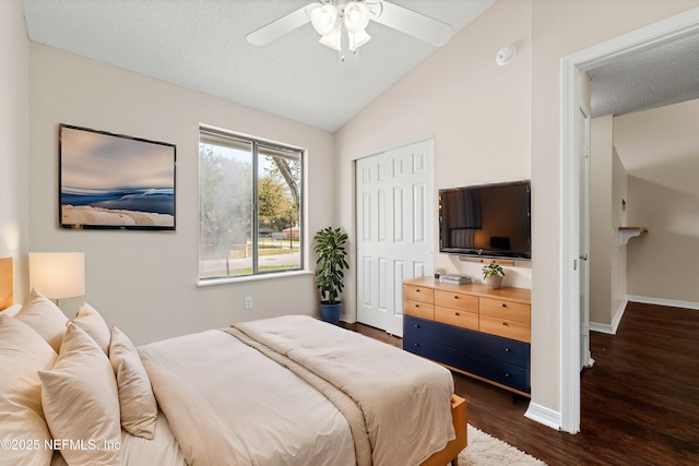 bedroom with dark wood-style floors, a closet, vaulted ceiling, a textured ceiling, and baseboards