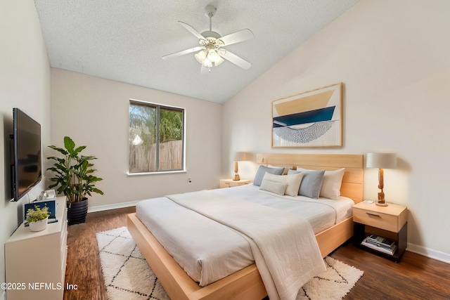 bedroom with vaulted ceiling, a textured ceiling, baseboards, and wood finished floors