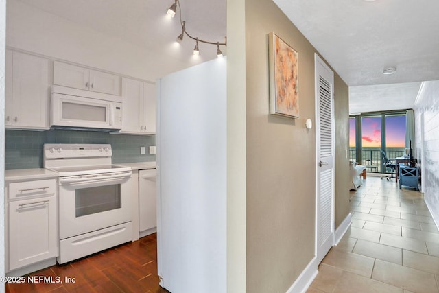 kitchen with white appliances, baseboards, white cabinets, decorative backsplash, and light countertops