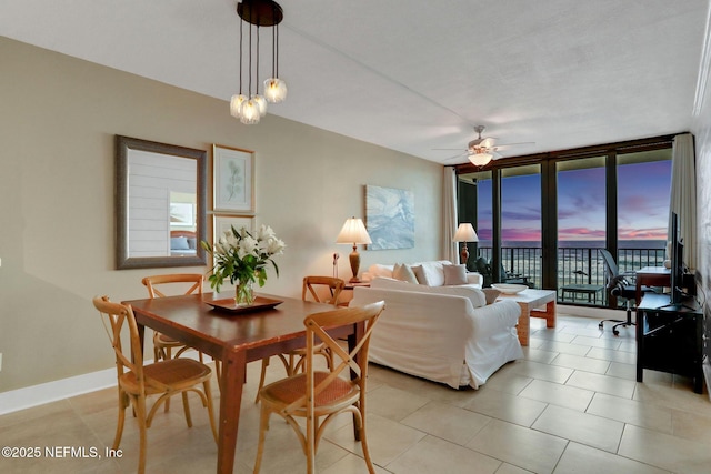 dining room with a wall of windows, light tile patterned flooring, a ceiling fan, and baseboards