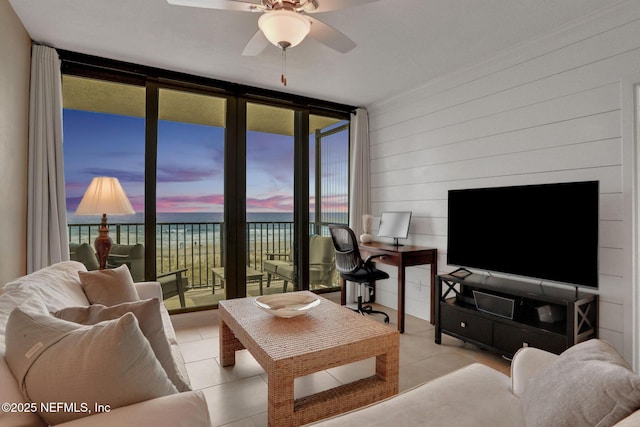 tiled living room with ceiling fan and a wall of windows