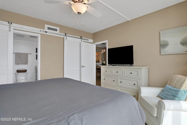 bedroom featuring ceiling fan, a barn door, and visible vents