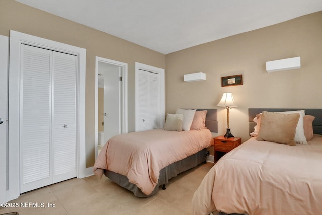 bedroom with light tile patterned floors, ensuite bath, and two closets