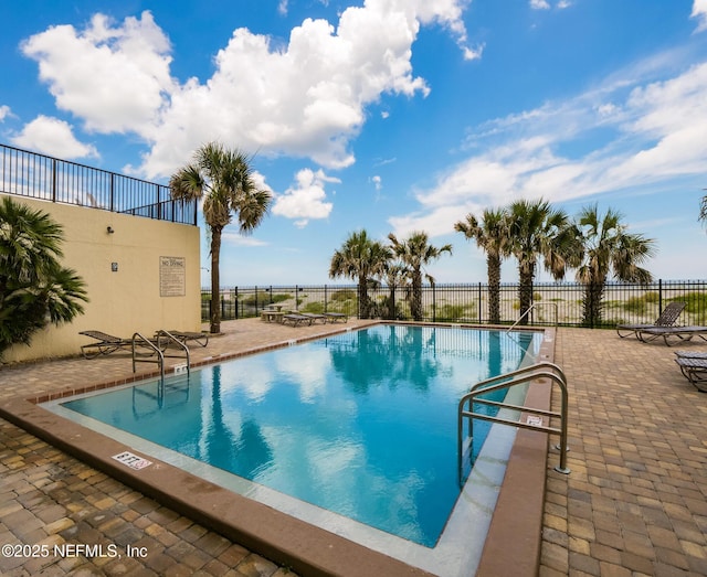 community pool with a patio area and fence