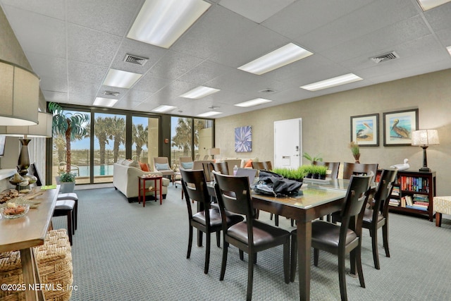 carpeted dining room with a wall of windows, a paneled ceiling, and visible vents