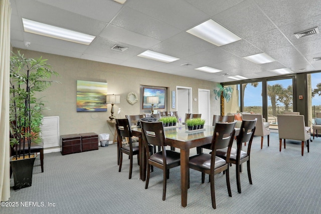 dining space with carpet floors, a paneled ceiling, and visible vents