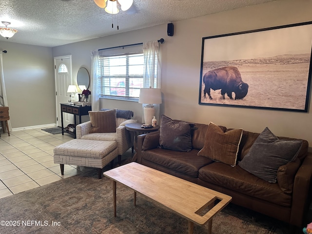 living area featuring ceiling fan, a textured ceiling, baseboards, and light tile patterned floors