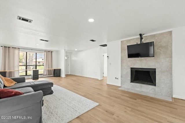 living room with visible vents, a tiled fireplace, and wood finished floors