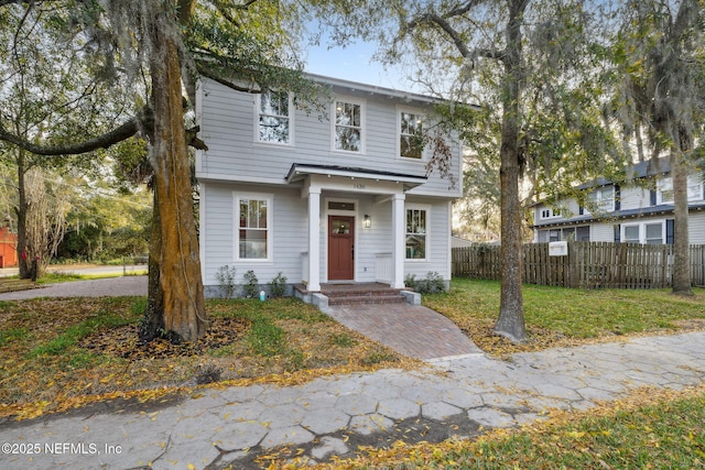 colonial inspired home featuring a front lawn and fence