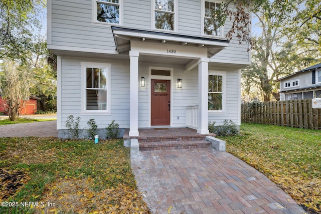 entrance to property featuring fence and a lawn