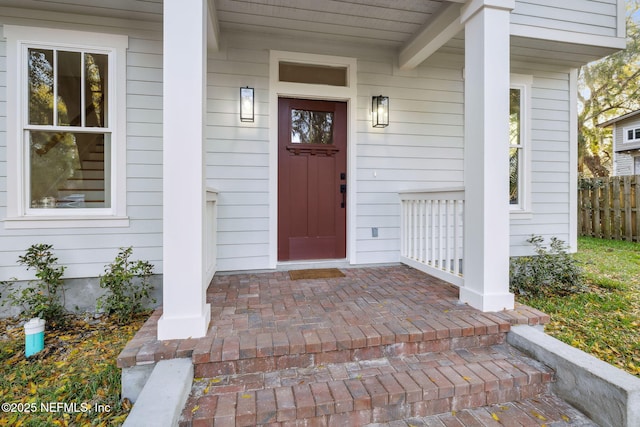 property entrance featuring a porch and fence