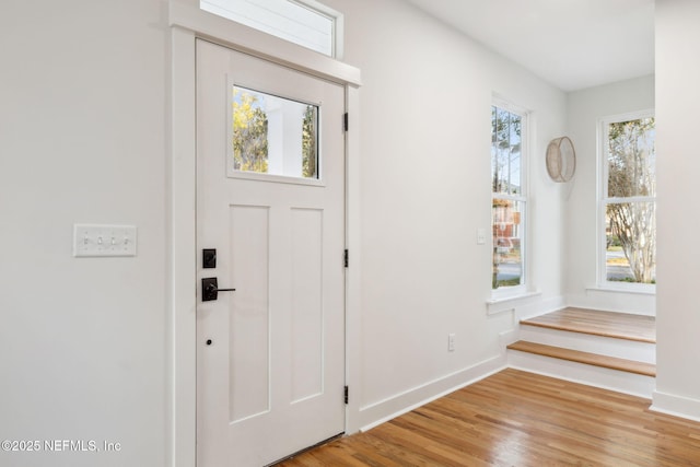 foyer entrance with baseboards and light wood-style floors