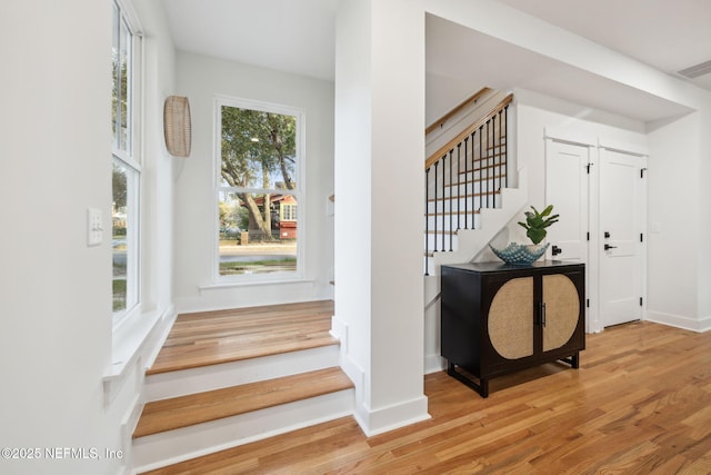 stairs with wood finished floors, visible vents, and baseboards