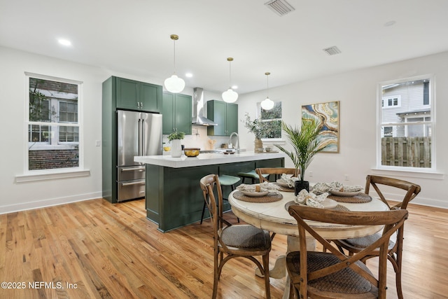 dining area with visible vents, light wood-style flooring, and baseboards