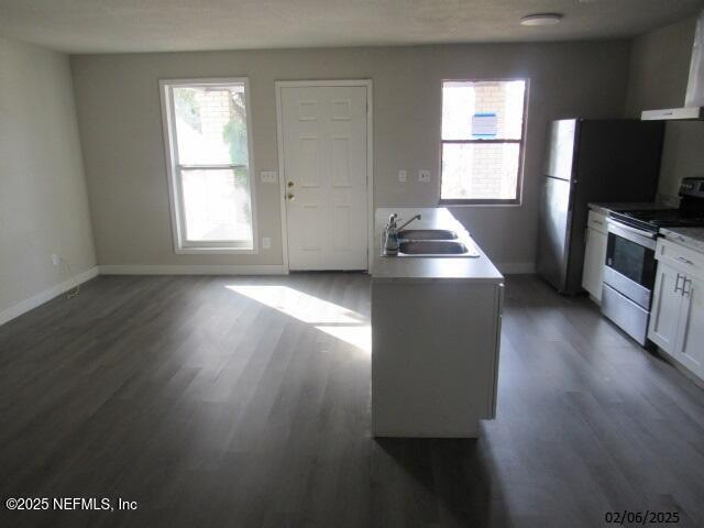 kitchen with white cabinets, electric stove, wall chimney exhaust hood, dark wood-type flooring, and a sink