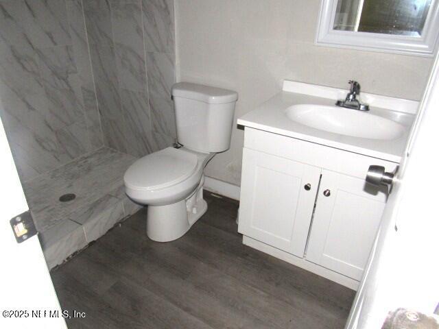 full bath with toilet, a shower stall, wood finished floors, and vanity