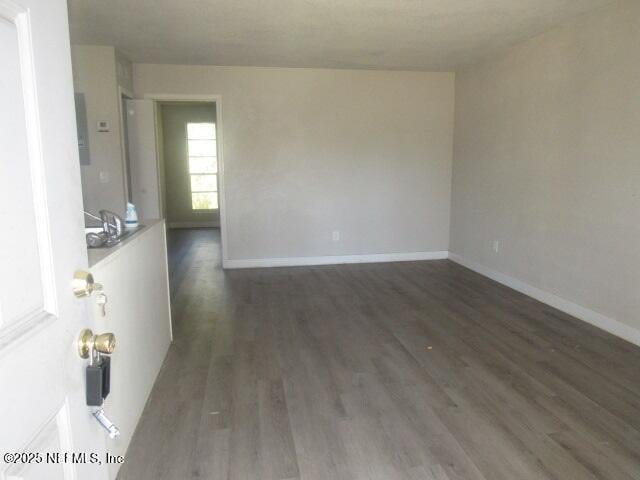 spare room with baseboards and wood finished floors