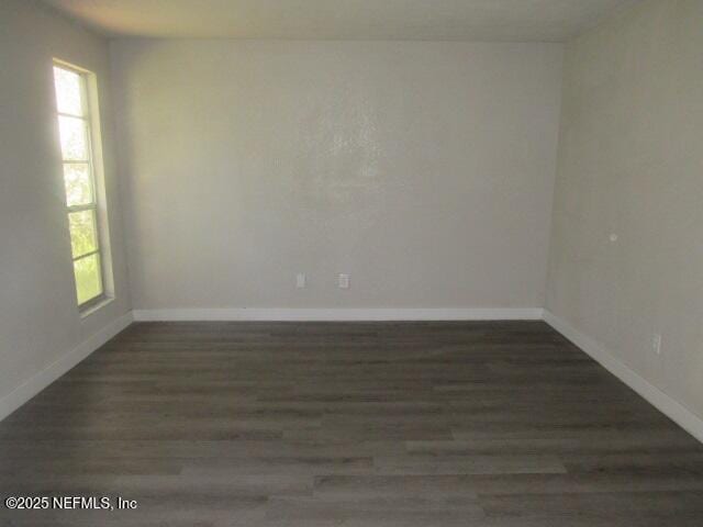 spare room featuring baseboards and wood finished floors