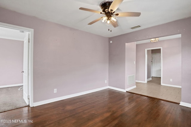 unfurnished room with baseboards, visible vents, ceiling fan, and wood finished floors