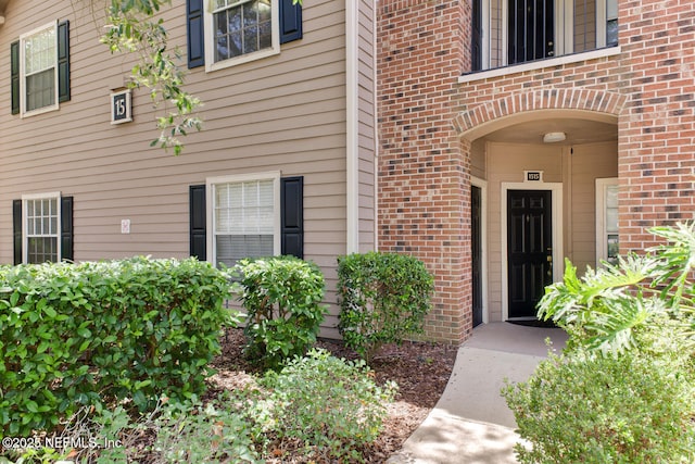 view of exterior entry featuring brick siding