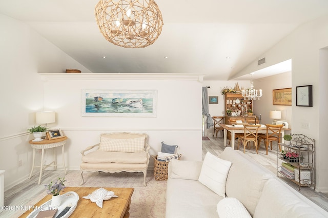 living area with lofted ceiling, visible vents, and a chandelier