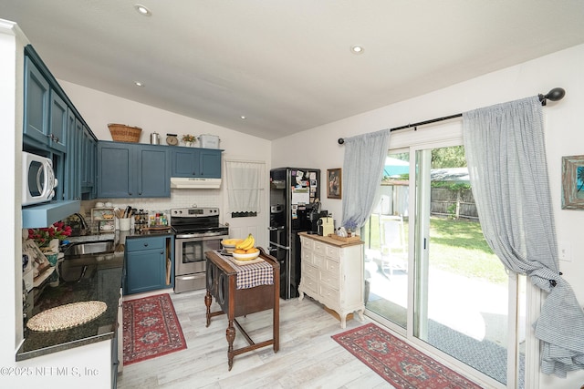 kitchen with white microwave, under cabinet range hood, electric range, a sink, and vaulted ceiling