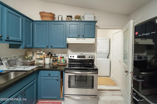 kitchen with blue cabinetry, stainless steel electric range, stacked washer and clothes dryer, and under cabinet range hood