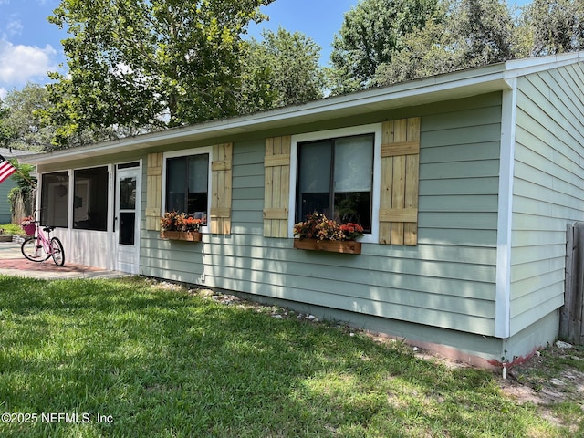 view of front of home featuring a sunroom and a front lawn