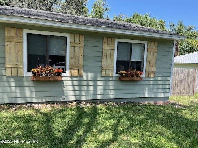 view of side of home featuring fence and a yard