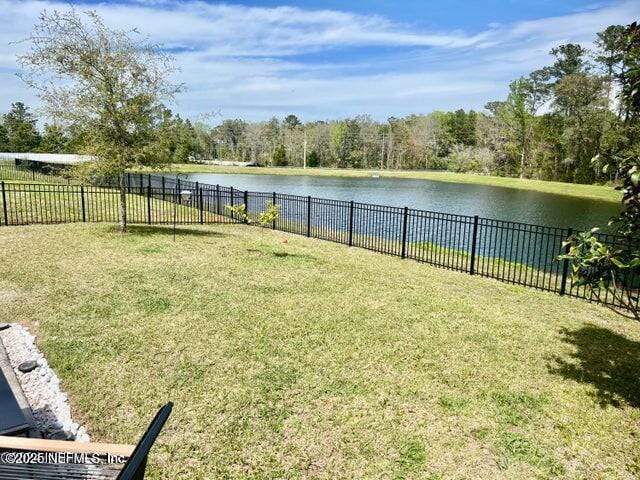 view of yard with a fenced backyard and a water view