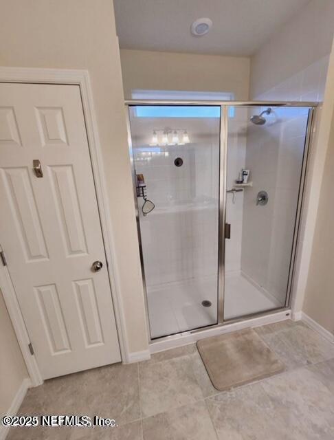 bathroom with a shower stall and baseboards