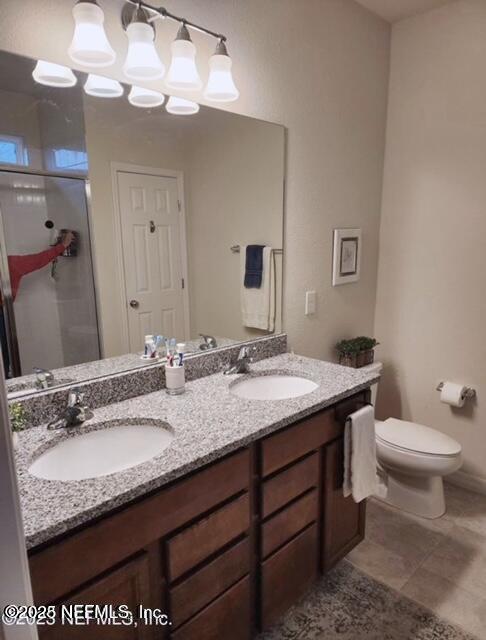 bathroom with a shower stall, toilet, double vanity, and a sink