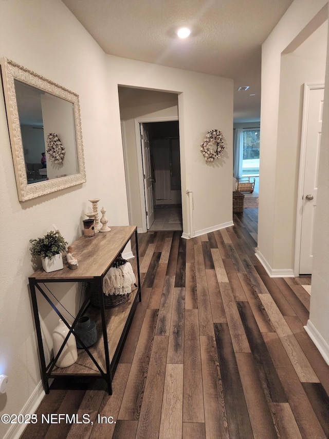 hallway with dark wood-type flooring and baseboards