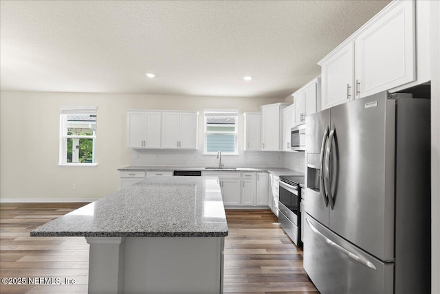 kitchen featuring a center island, plenty of natural light, dark wood-style floors, and stainless steel appliances