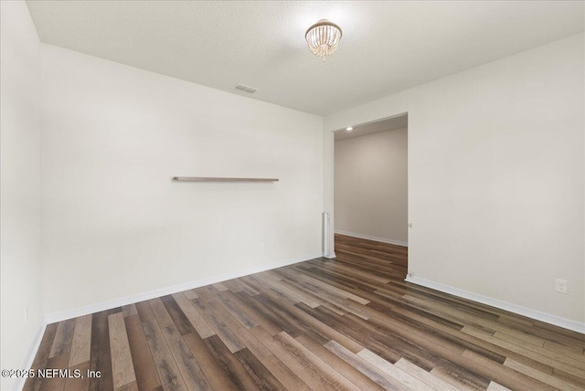 empty room with baseboards, wood finished floors, and visible vents