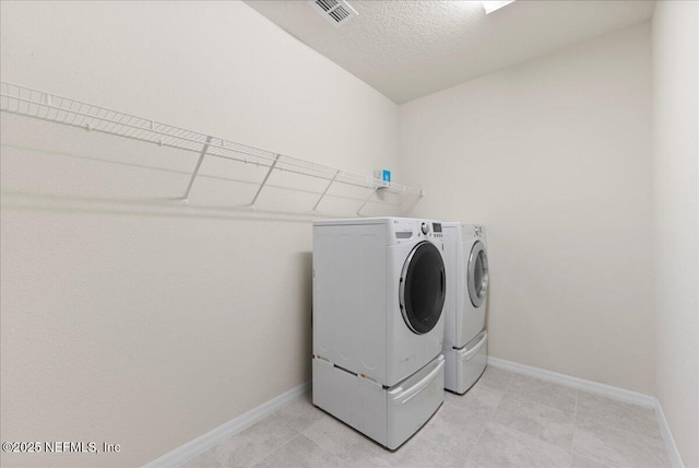 clothes washing area with laundry area, baseboards, washing machine and dryer, and visible vents