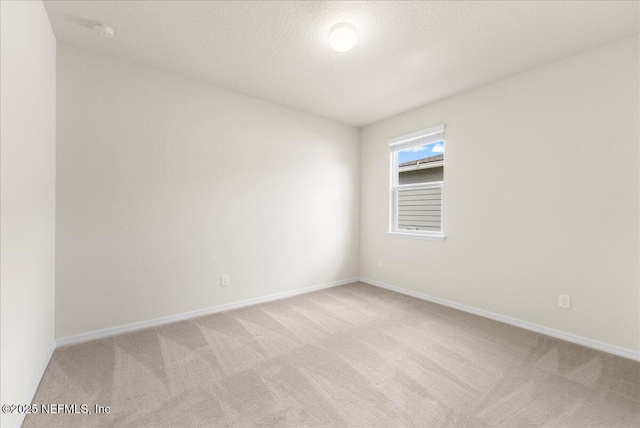 spare room featuring a textured ceiling, baseboards, and light colored carpet