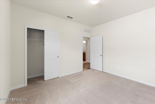 unfurnished bedroom featuring visible vents, carpet, baseboards, and a closet